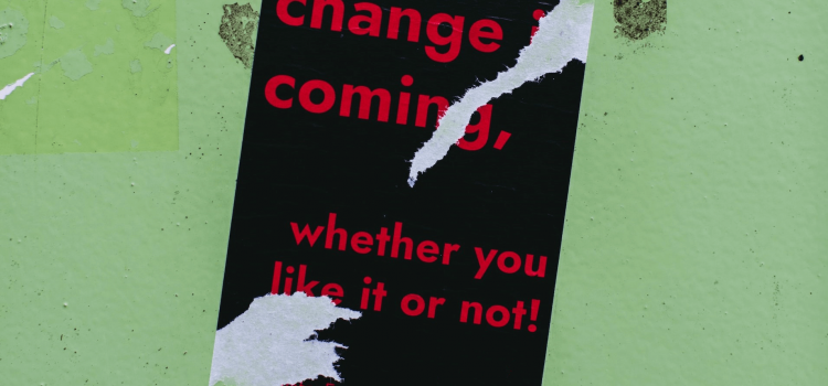 Poster with black background and red letters saying 'Change is coming, whether you like it or not'.